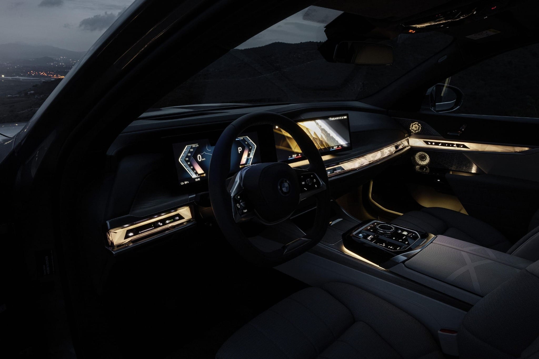 The interior of a BMW 7 Series at dusk, lit by warm ambient cabin lighting.