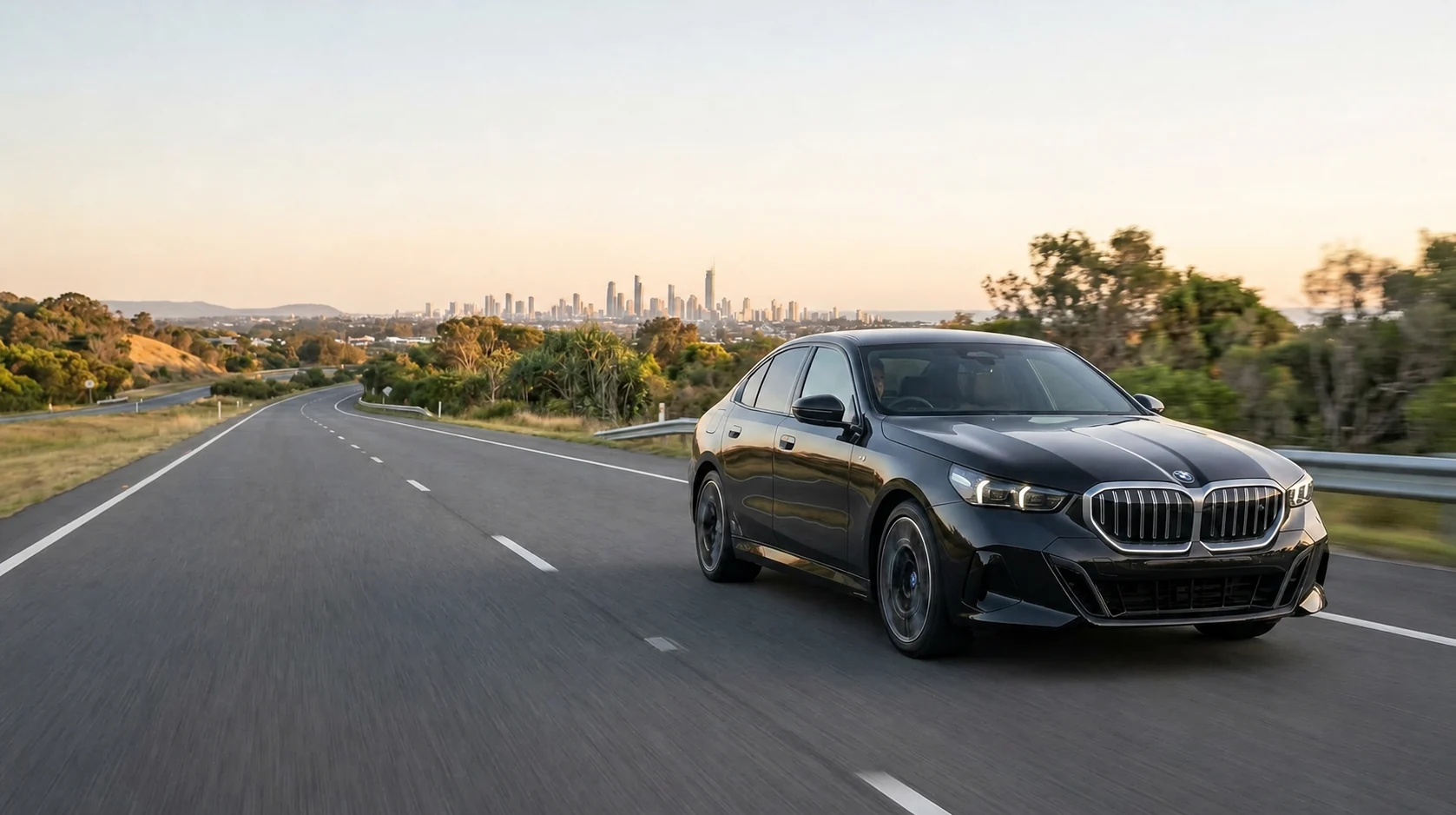 A black BMW 5 Series travelling toward the Gold Coast at sunset.
